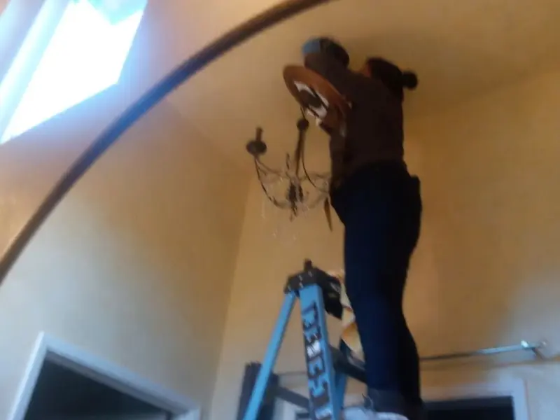Electrician installing a chandelier in a Vidalia residence
